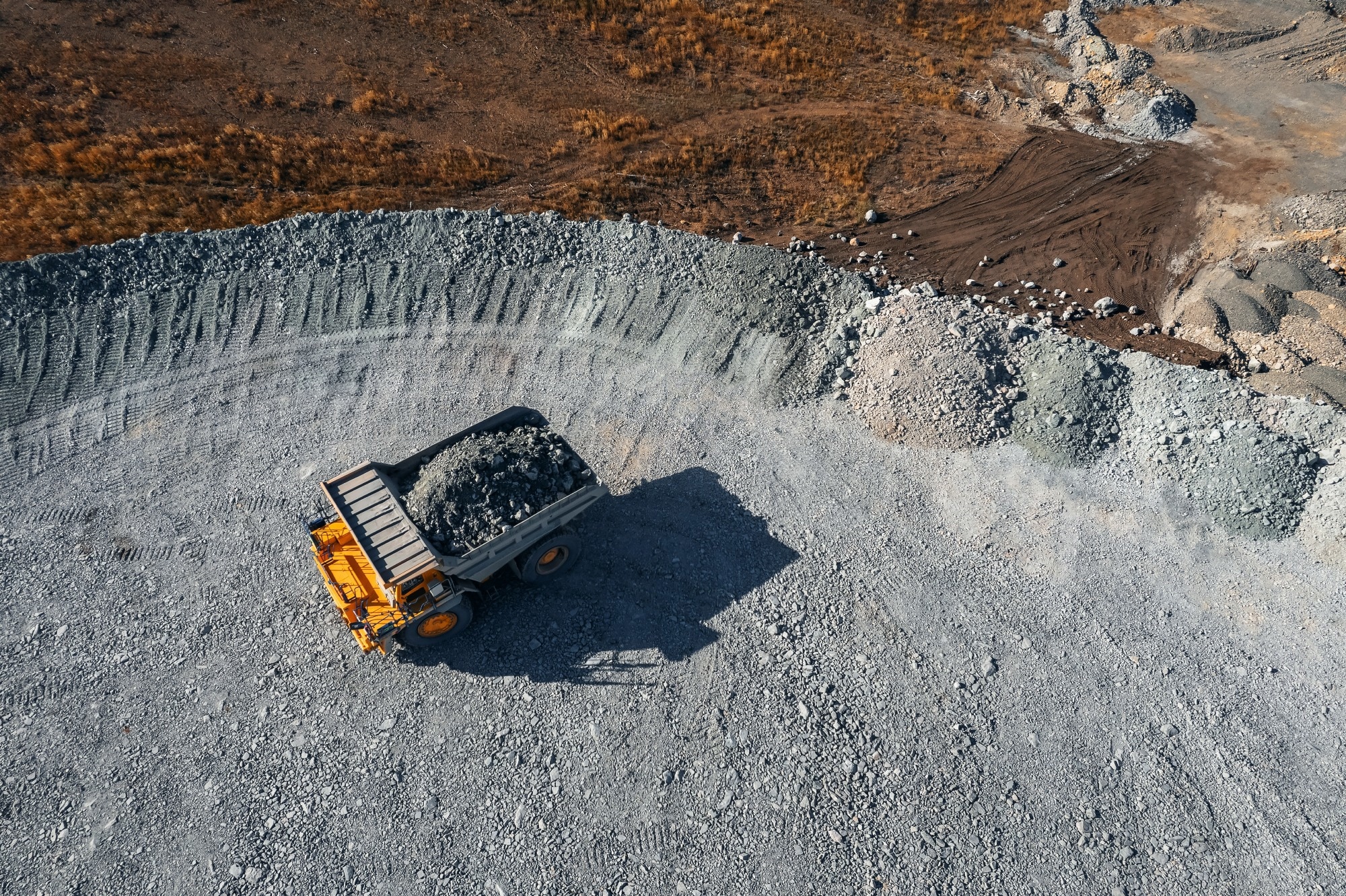 Big yellow mining truck transportation of gold and iron, copper ore. Open pit mine industry, aerial view from drone.