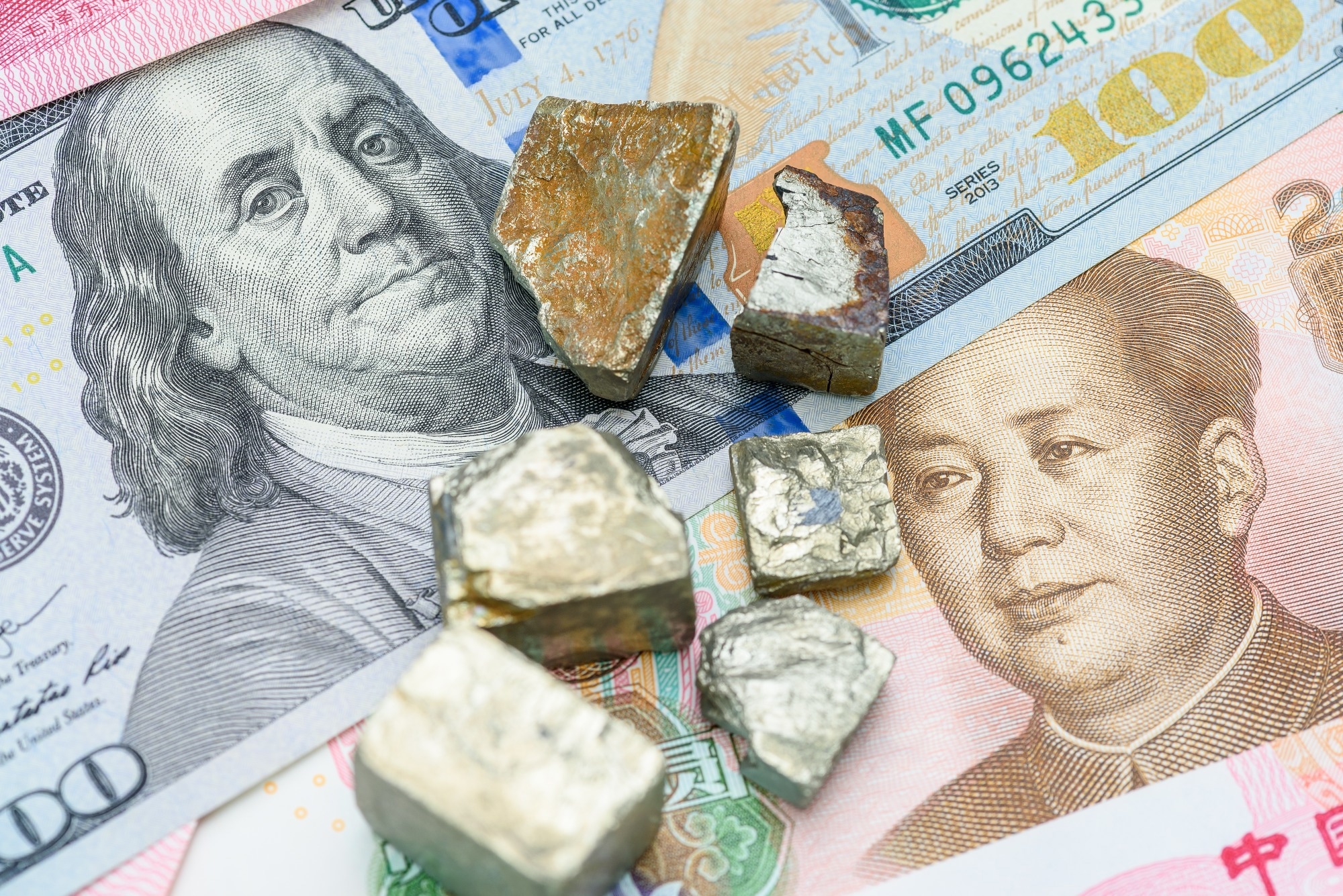 Critical minerals on top of a $100 US banknote and a Chinese yuan note.