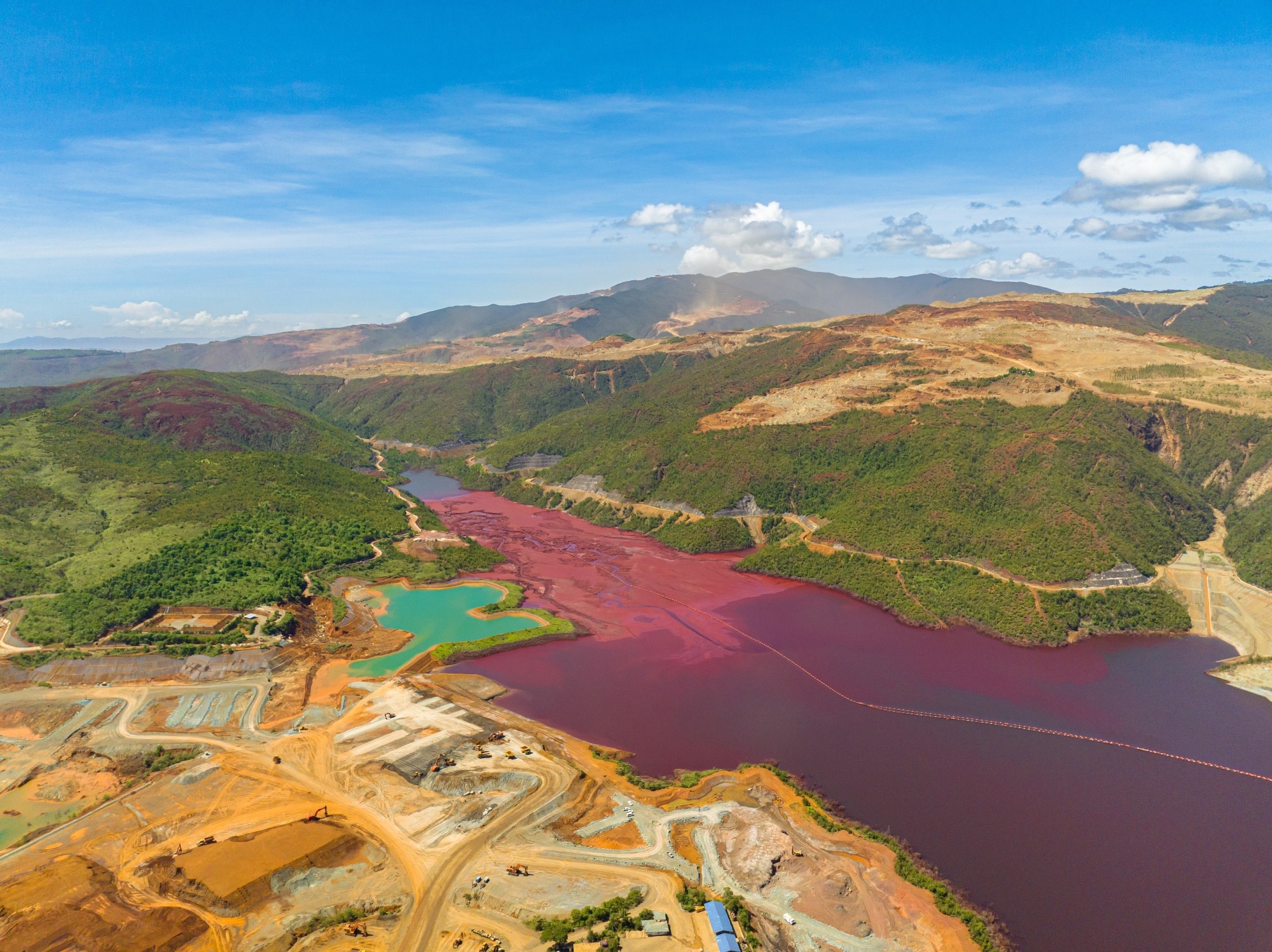 Open pit nickel mine and burgundy water lake. Polluted air and water. Mindanao, Philippines.