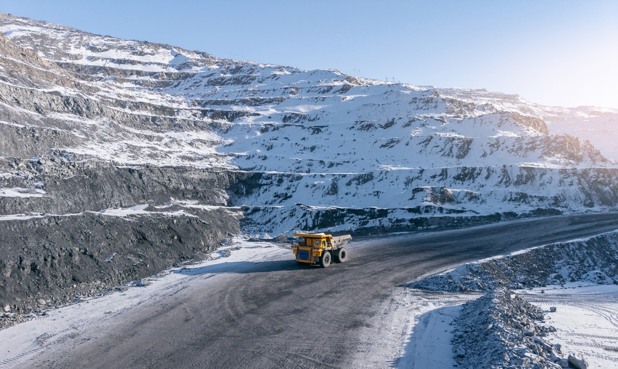 Open-pit coal mine with big yellow truck in winter landscape